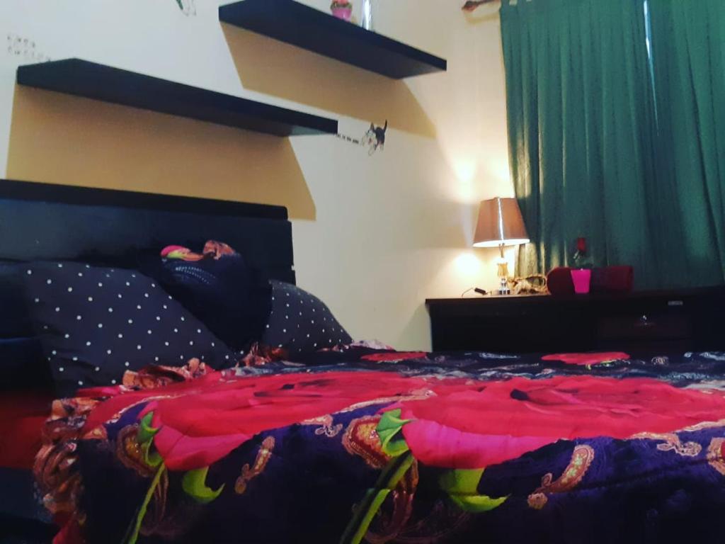 - une chambre avec un lit et une couverture rouge dans l'établissement Margonda residence 1& 2 by andrew, à Pondokcina