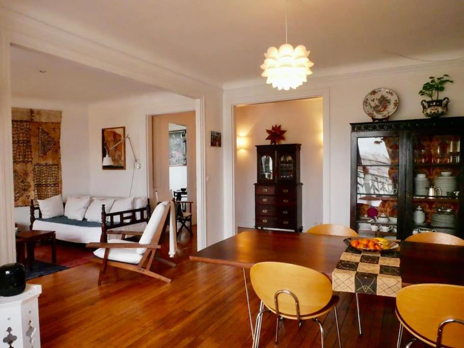 uma sala de estar com um sofá, uma mesa e cadeiras em Superbe appartement de 120m2 en plein Paris em Paris