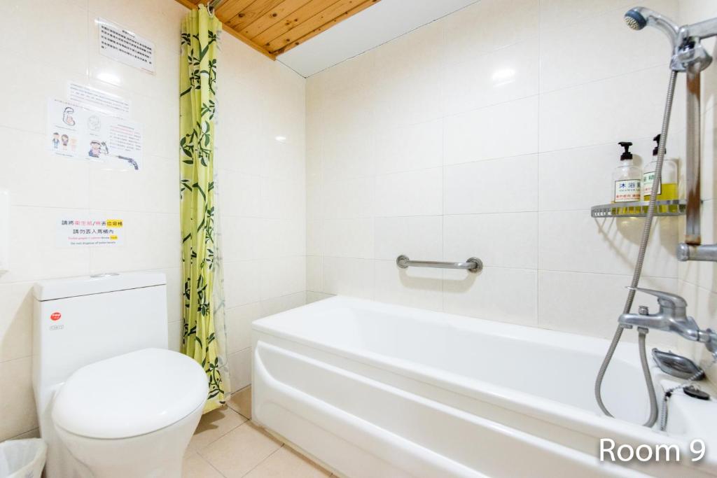 a bathroom with a white tub and a toilet at Gwawa Hotel in Kaohsiung