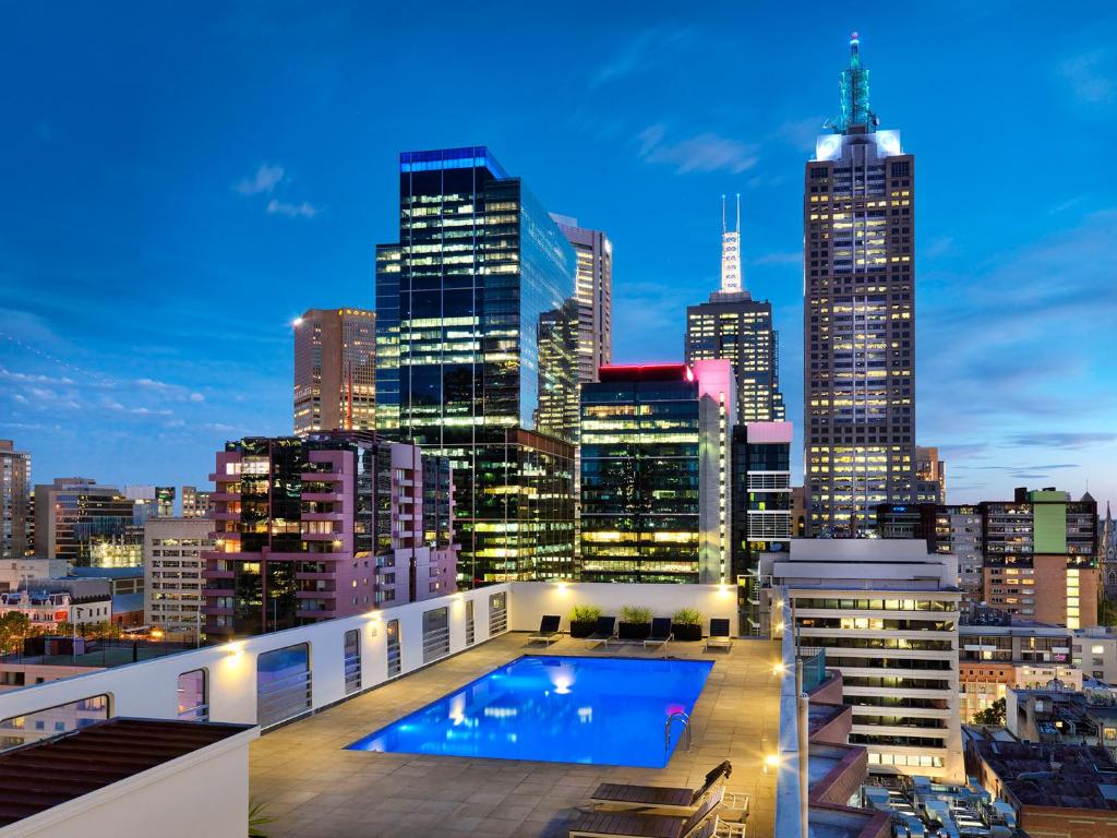 a view of a city skyline at night with a swimming pool at Hotel Grand Chancellor Melbourne in Melbourne