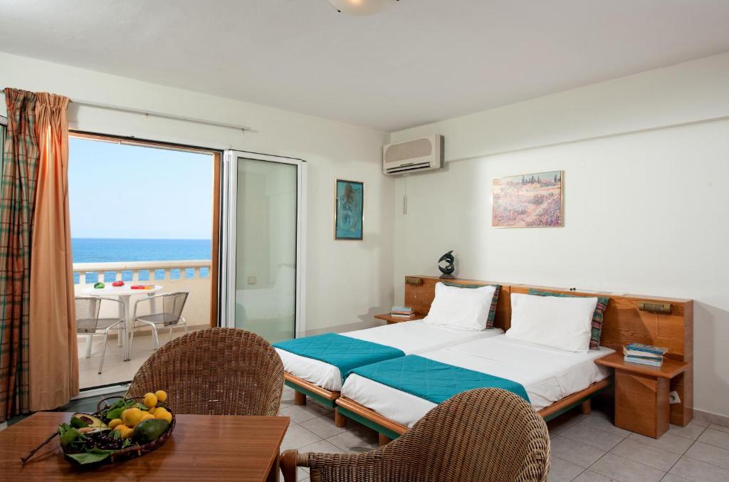 a bedroom with a bed and a balcony with the ocean at Andromeda Apartments & Studios in Hersonissos