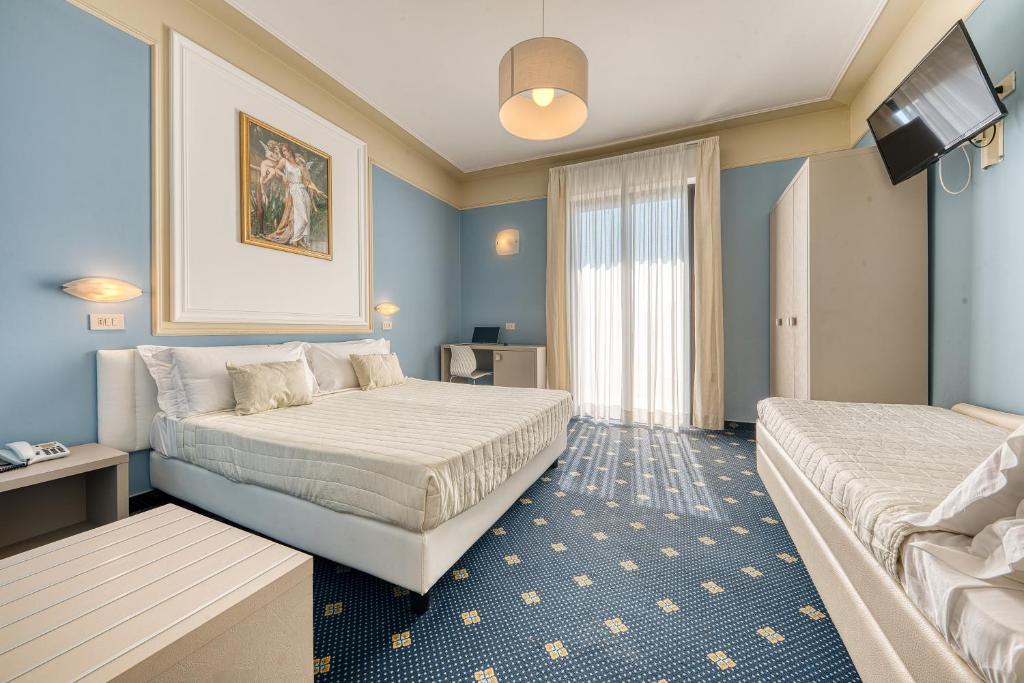 リミニにあるホテル オーガスタスのベッド2台とテレビが備わるホテルルームです。