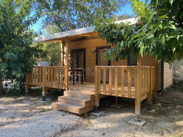 Cette petite cabane en bois dispose d'une terrasse couverte et d'une table. dans l'établissement Lodges & Nature - 71, à Avignon
