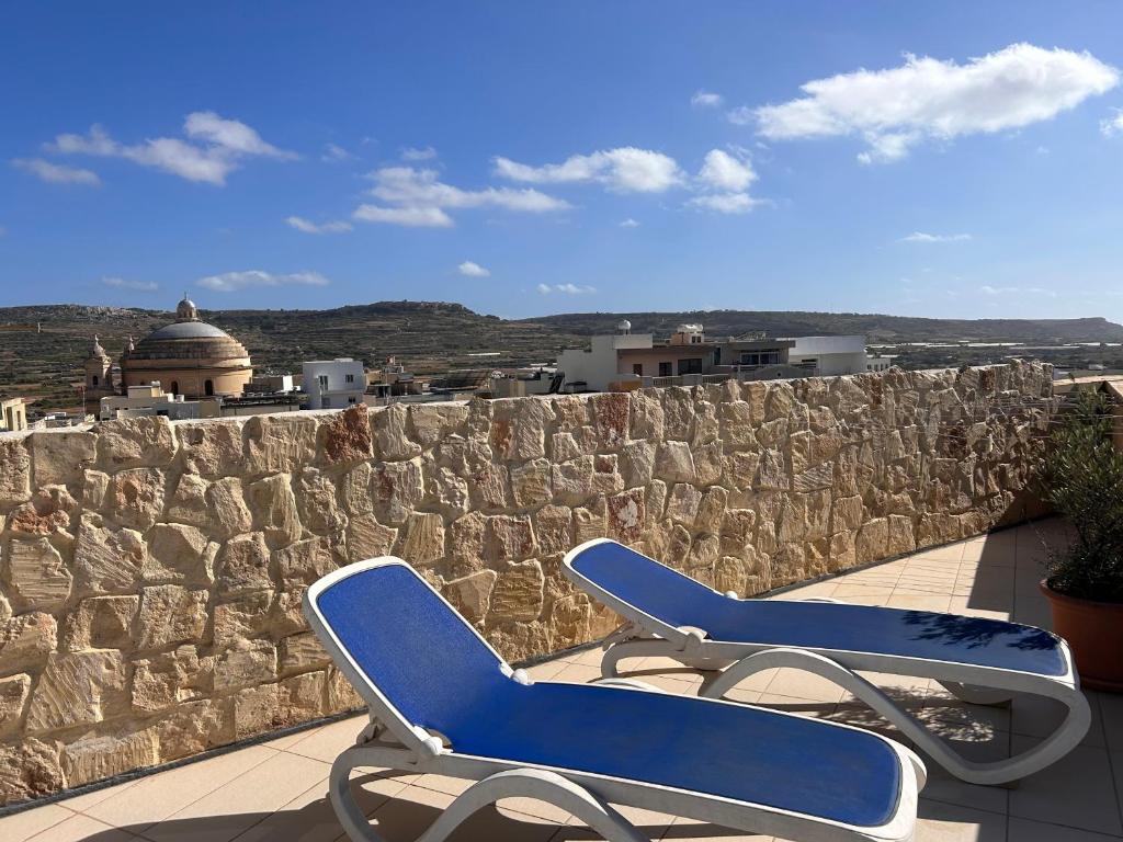 una silla azul sentada en la parte superior de una pared de piedra en Claureece Court Mgarr, en Mġarr