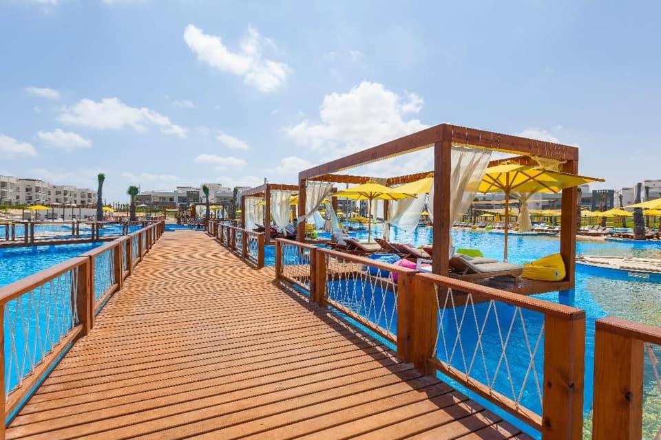 einen hölzernen Pier mit Stühlen und Sonnenschirmen auf dem Wasser in der Unterkunft Amwaj North Cost VIP Chalet in El-Alamein