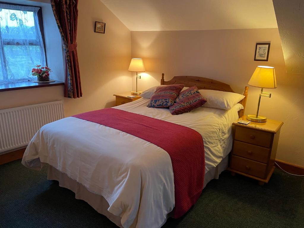 a bedroom with a bed with two lamps and a window at Middle Flass Lodge in Bolton by Bowland