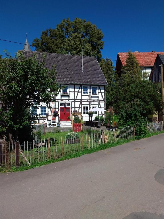 a white house with a red door on a street at Appartement an der Bicke in Dehringhausen