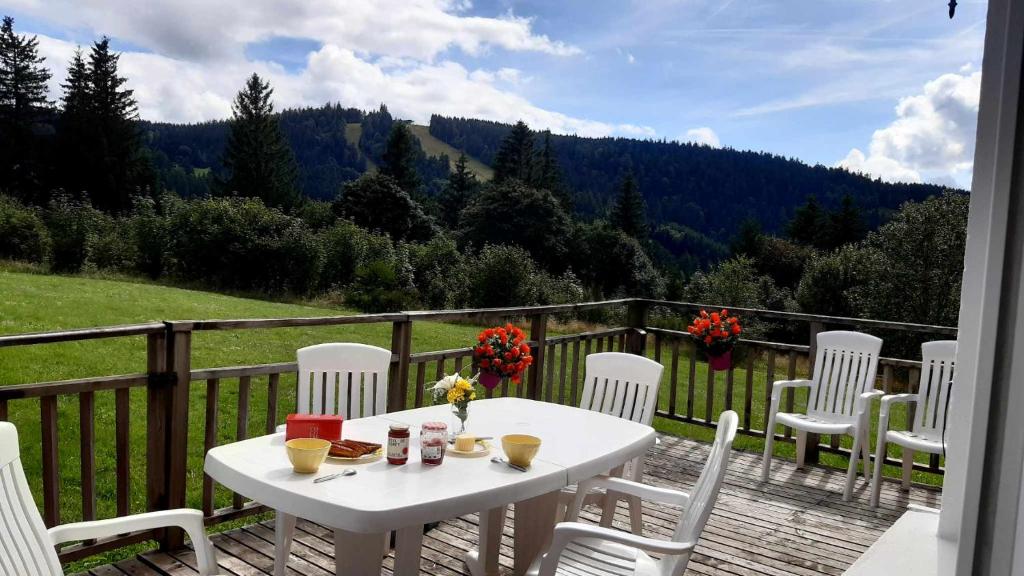 une table et des chaises blanches sur une terrasse en bois dans l'établissement Les Angéliques, à Gérardmer