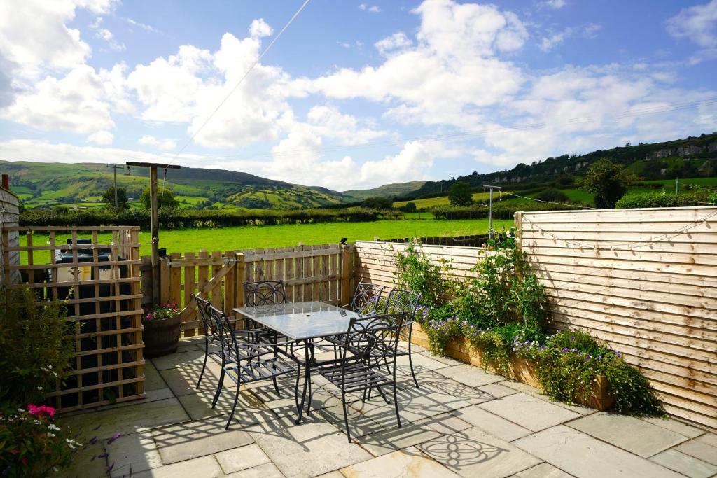 un patio con tavolo, sedie e una recinzione di Gortnagory Cottage Carnlough a Carnlough