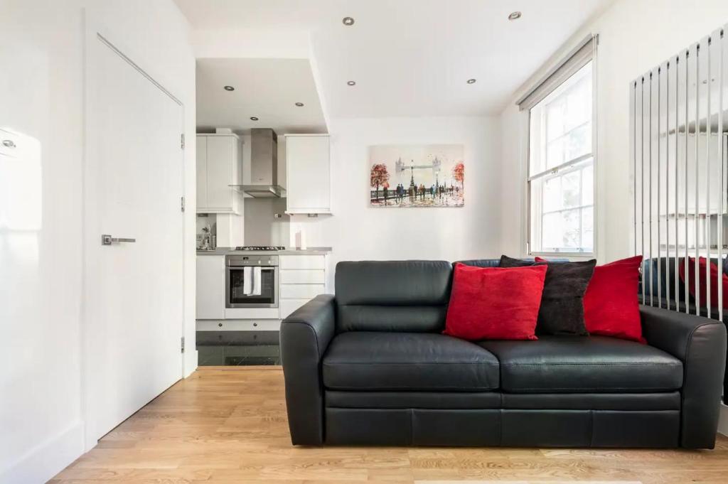 salon z czarną kanapą i czerwonymi poduszkami w obiekcie Lovely one bedroom in the heart of London w Londynie
