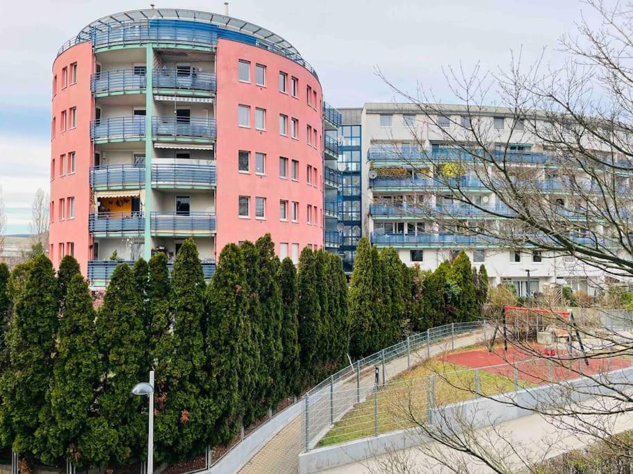 a pink building with a playground in front of trees at Wien an Donau in Vienna