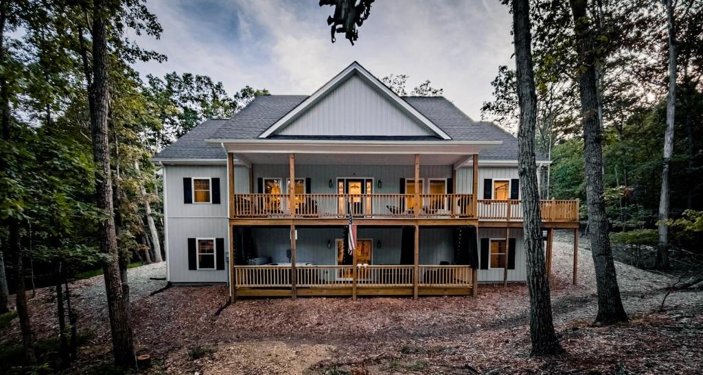 a house with a large deck in the woods at Season 4 Escape - Managed by Gr8Escapes in Massanutten