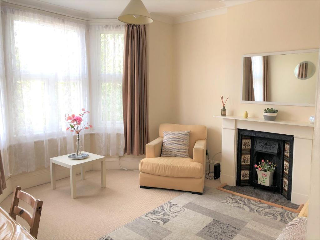 a living room with a chair and a fireplace at Spacious West London 2 Bedroom Apartment in London