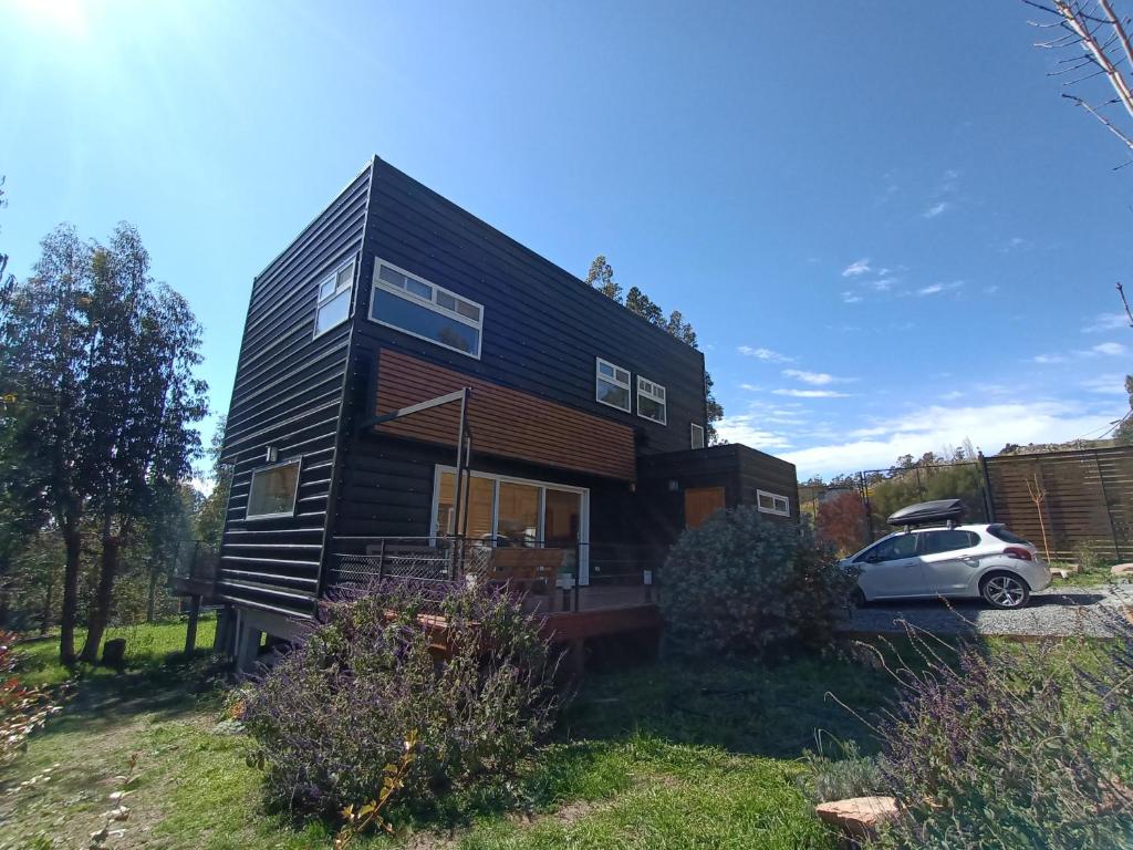 una casa negra con un coche aparcado delante de ella en EcoHaus en la sierra en Tandil