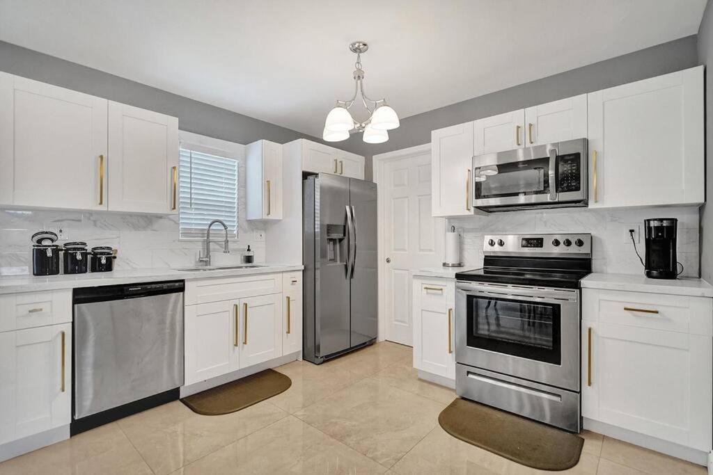 uma cozinha com armários brancos e electrodomésticos de aço inoxidável em Luxury 3bd/2ba near Beach & Las Olas em Fort Lauderdale