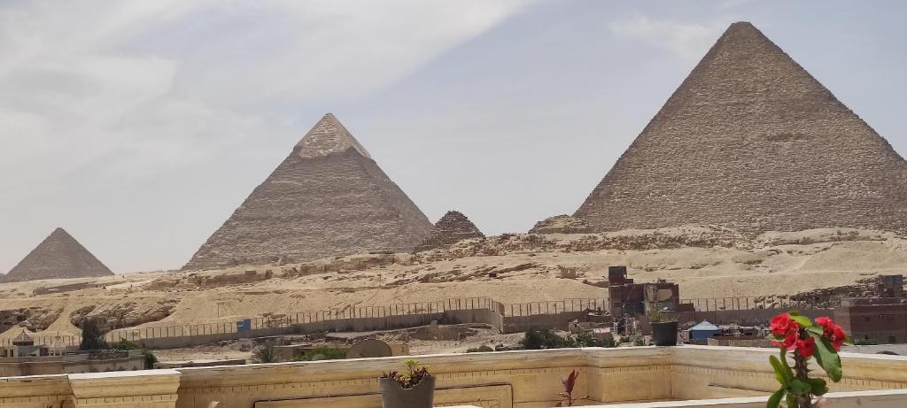 een uitzicht op de piramides van Giza met een rode bloem bij Mamado PYRAMIDS VIEW in Caïro