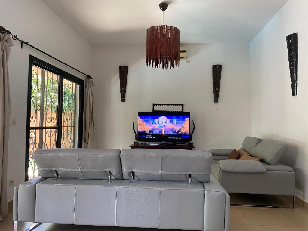 a living room with a couch and a tv at Villa Dallie in Saly Portudal
