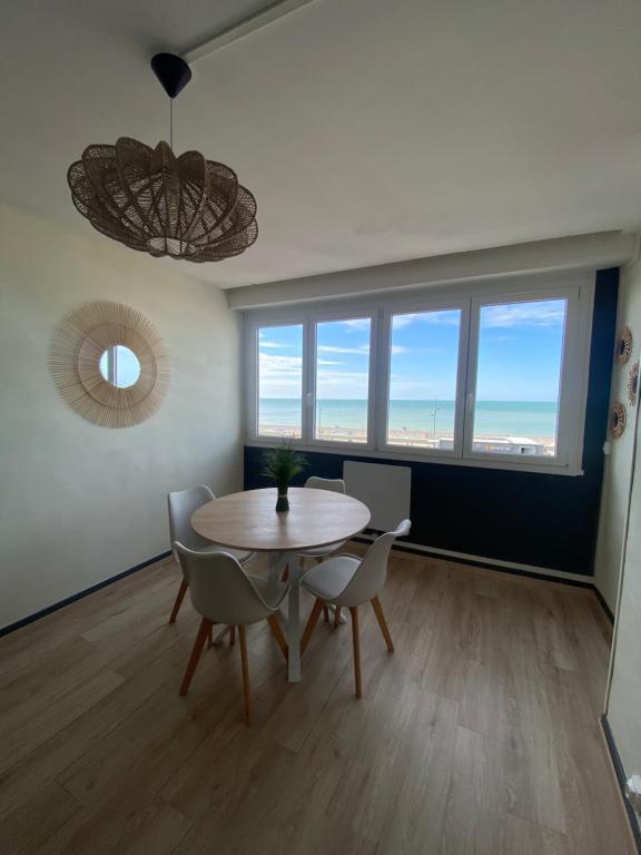 une salle à manger avec une table, des chaises et des fenêtres dans l'établissement Les anges bleus, au Tréport