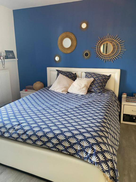 een blauwe slaapkamer met een bed en twee spiegels aan de muur bij chez Sylvia in Bonneuil-sur-Marne