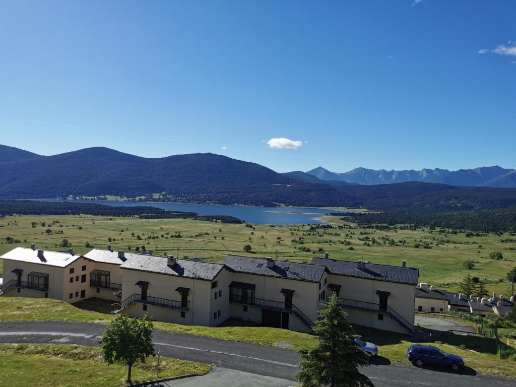 un groupe de bâtiments dans un champ avec un lac dans l'établissement Duplex avec vue lac, résidence la Singlantane, aux Angles