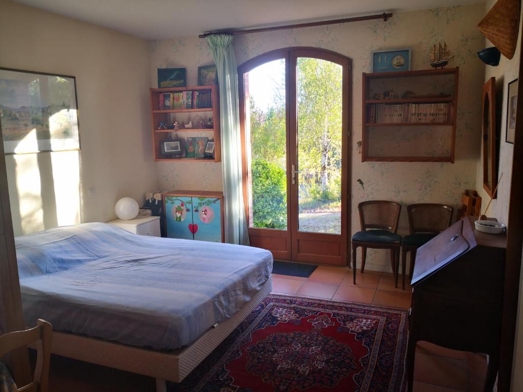 a bedroom with a bed and a sliding glass door at Gîte indépendant - services dîner et petit-déjeuner possible in Deyme