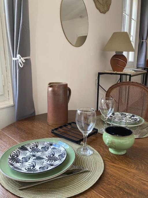 a wooden table with plates and wine glasses on it at Bel appartement hyper centre in Bernay