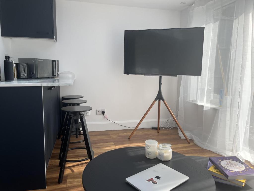 uma sala de estar com uma mesa e uma televisão de ecrã plano em Newly refurbished 1-Bed Apartment in Croydon SE25 em Londres