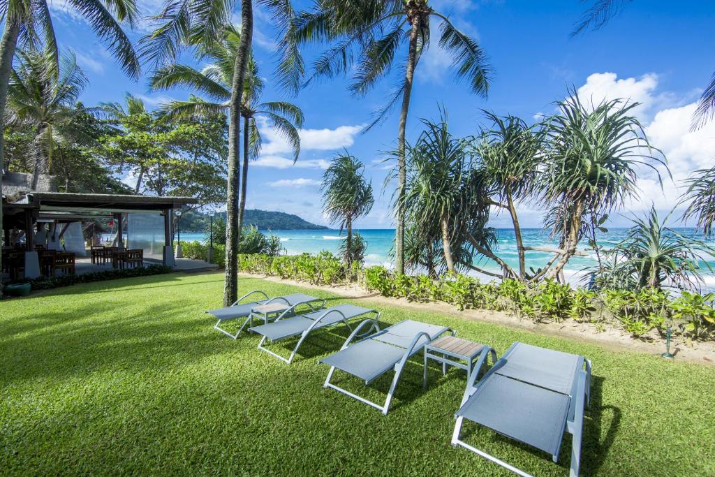 a row of lounge chairs on the grass near the beach at Katathani Phuket Beach Resort - SHA Extra Plus in Kata Beach