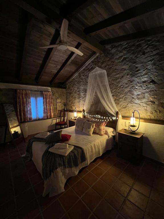 - une chambre avec un lit et un mur en pierre dans l'établissement El latido del Tiétar, à Lanzahita
