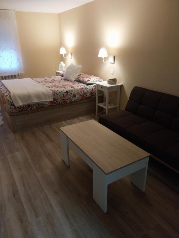 Habitación de hotel con cama, sofá y mesa en Un Rincón Tranquilo., en Manzanares el Real