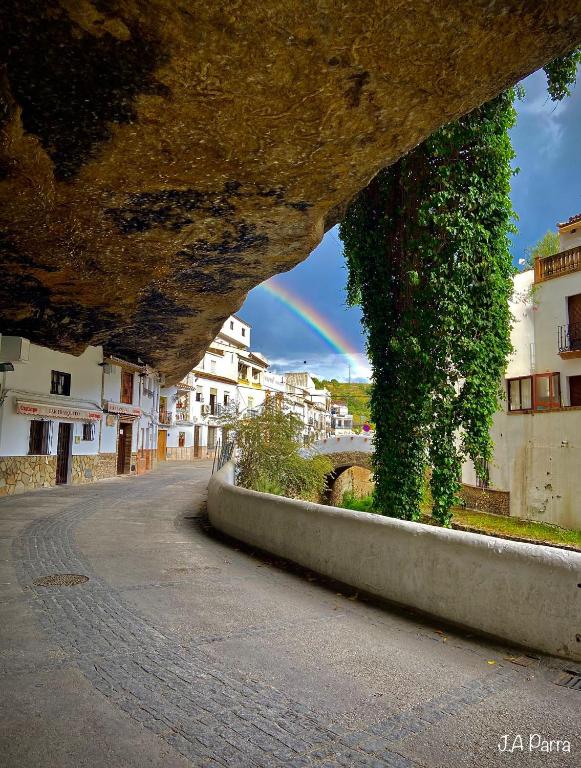 a rainbow in the sky over a street with buildings at Casa Cuevas del Sol in Setenil