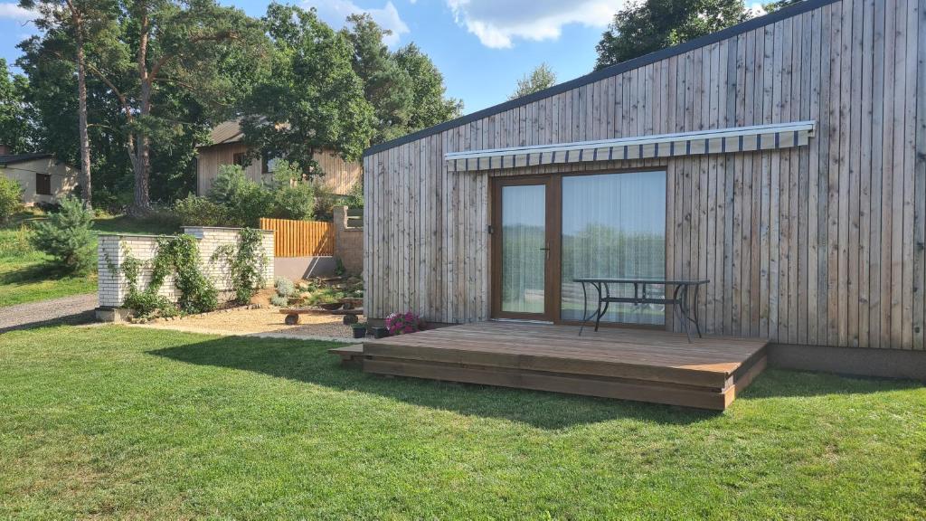 uma pequena cabina de madeira com uma mesa num deque em Orlická přehrada Chata Malá em Kožlí u Orlíka