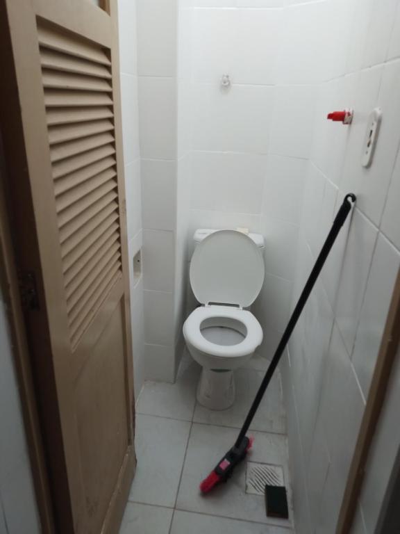 a bathroom with a toilet with a mop at Suíte em catete in Rio de Janeiro