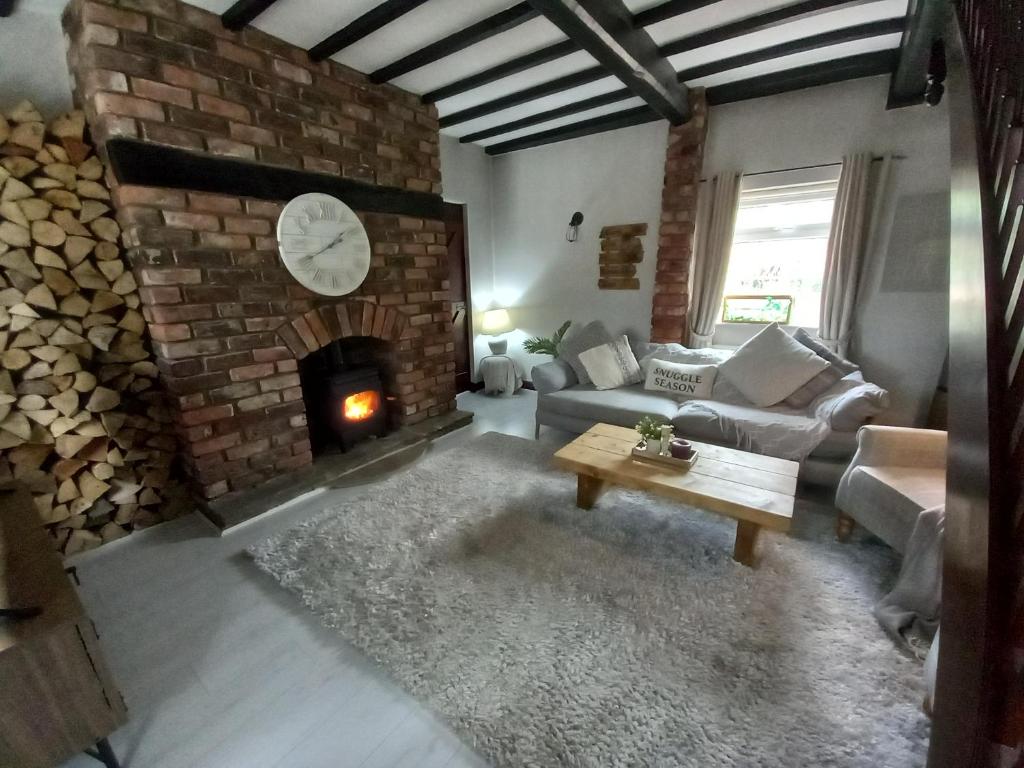 a living room with a fireplace and a couch and a table at Yewtree Cottage in Strensall