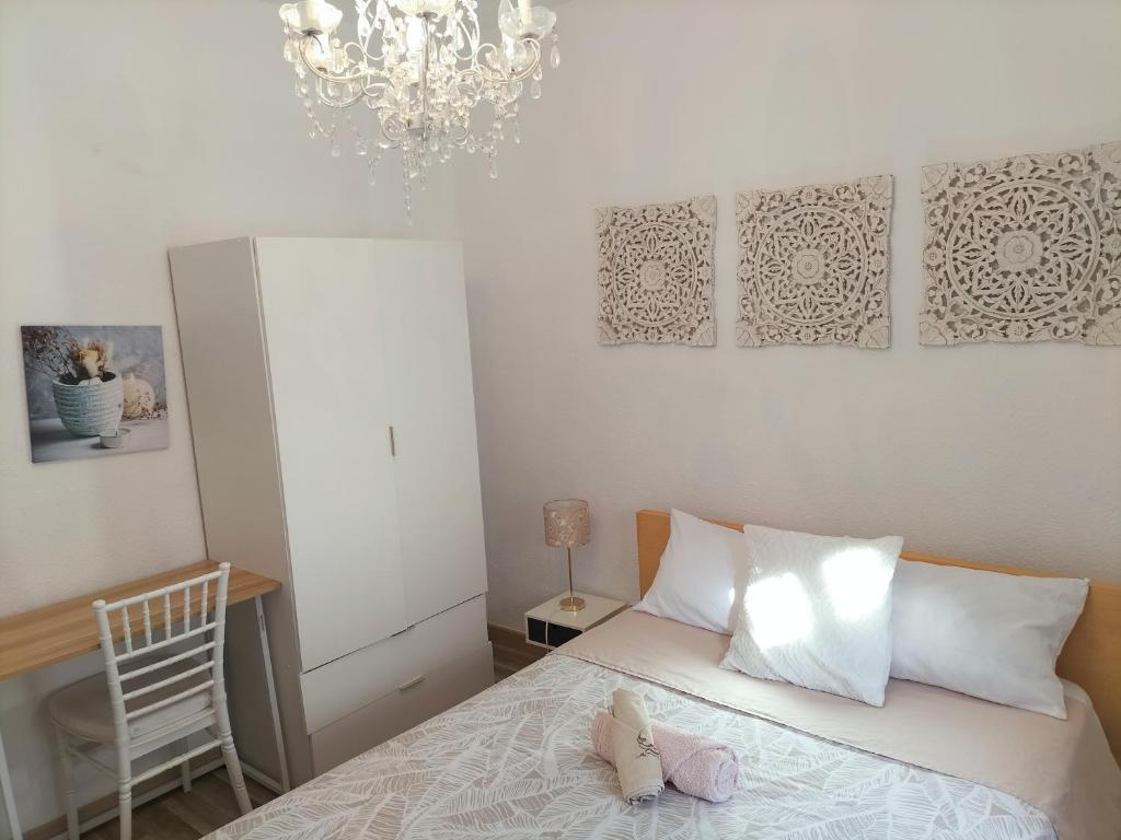 um quarto com uma cama com uma cadeira e um lustre em El Coqueto de Vallecas em Madri