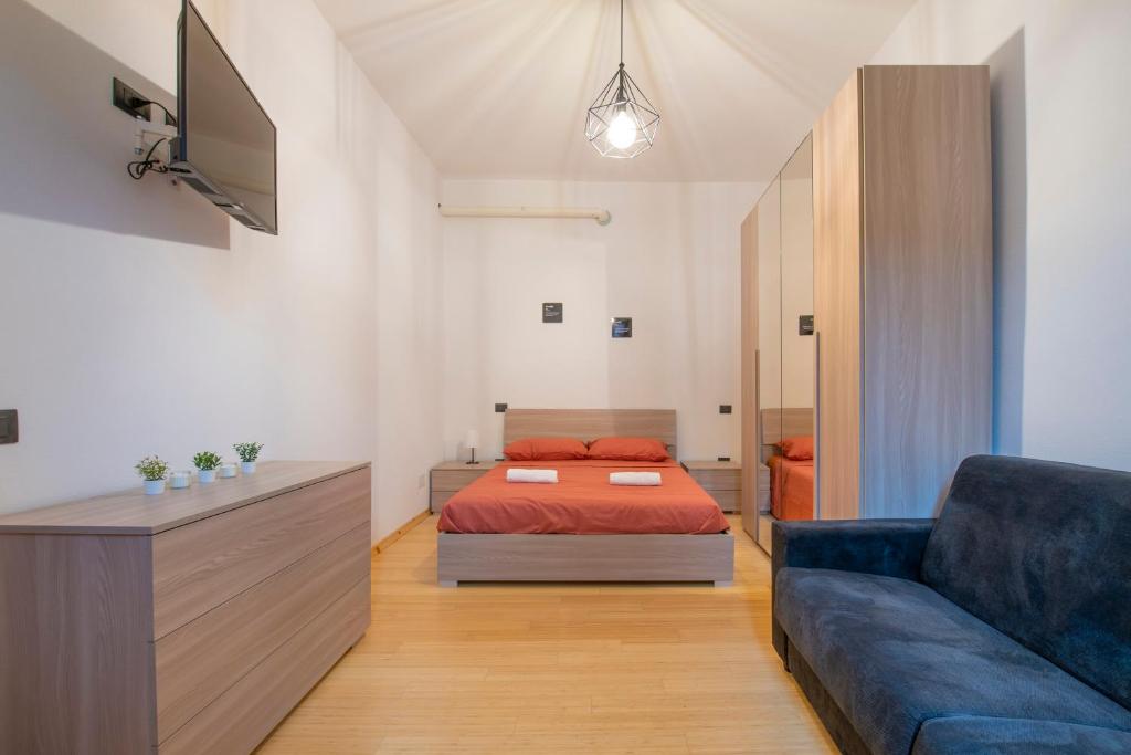 een slaapkamer met een bed en een bank bij [CantikHouse] free wifi & smarTV in Verona