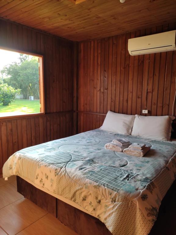 a bed in a wooden room with a window at POUSADA ROTA DOS BALÕES in Praia Grande