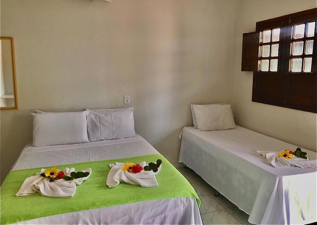 two beds in a room with flowers on them at Pousada Fragata in Porto De Galinhas