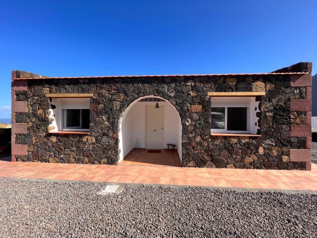 un edificio de piedra con una puerta blanca y dos ventanas en Casa Valentina El Hierro, en La Frontera