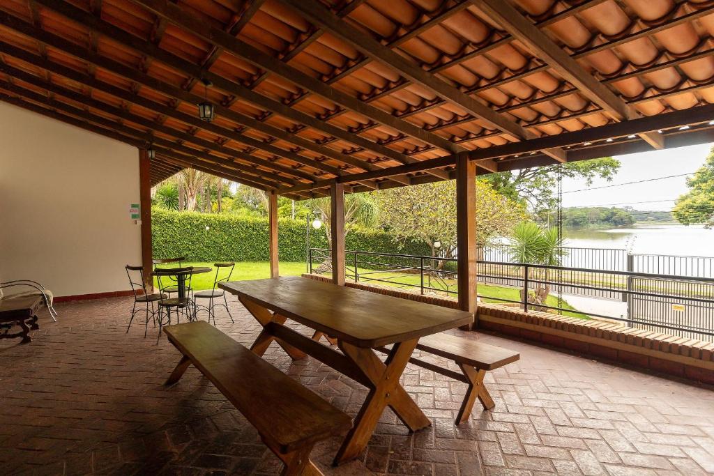 a picnic table and chairs on a patio with a view of the water at Pousada Wafeh Pampulha Suítes in Belo Horizonte