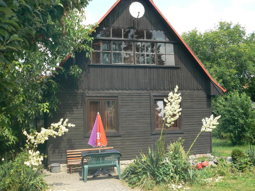 una casa con un banco y una sombrilla delante de ella en Rekreační chata Hradištko, en Hradišťko