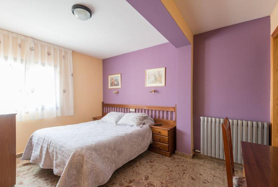 um quarto com paredes roxas, uma cama e uma janela em Casa Martina em Guadalaviar