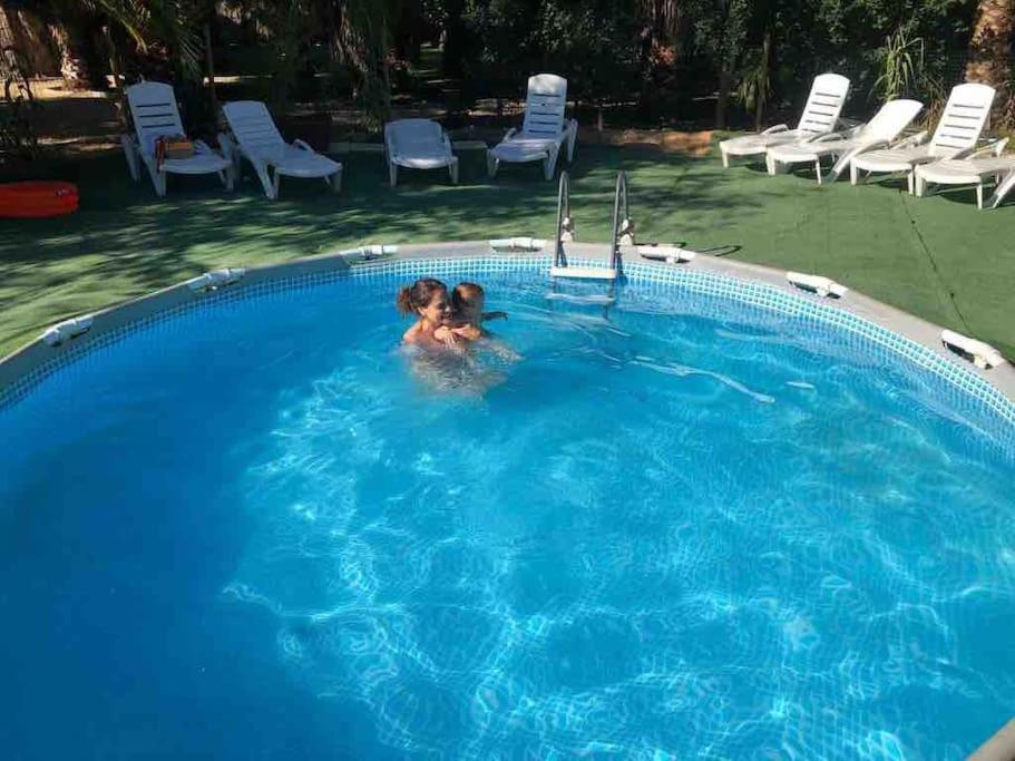 zwei Personen schwimmen in einem Pool in der Unterkunft CASA RURAL EN BOSQUE DE PALMERAS in Alberche del Caudillo