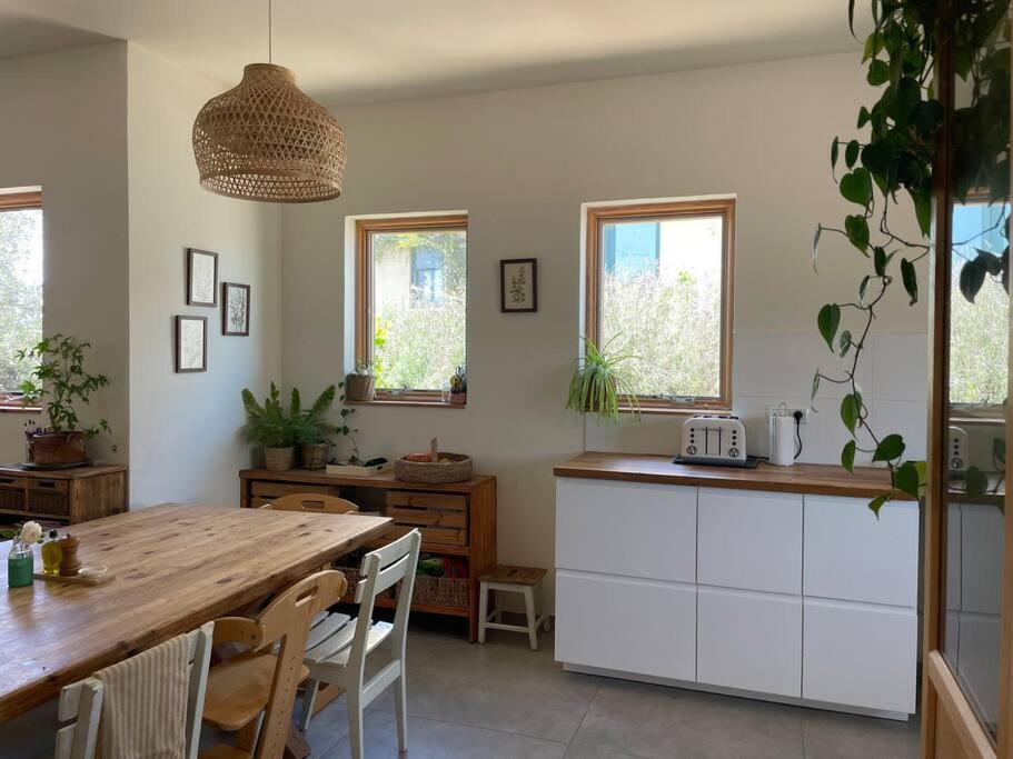 a kitchen with a wooden table and a dining room at Quiet cottage in the pastoral Galilee hills in Hararit