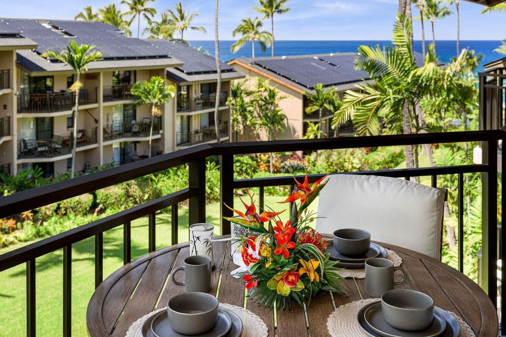 a table with cups and flowers on a balcony at Kona Makai 5307 in Kailua-Kona