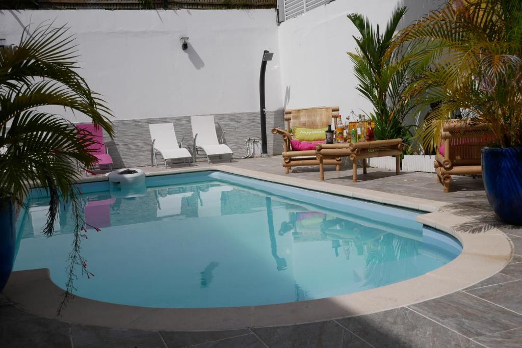a swimming pool in a yard with chairs and trees at Le colibri voyageur in Sans Pareil