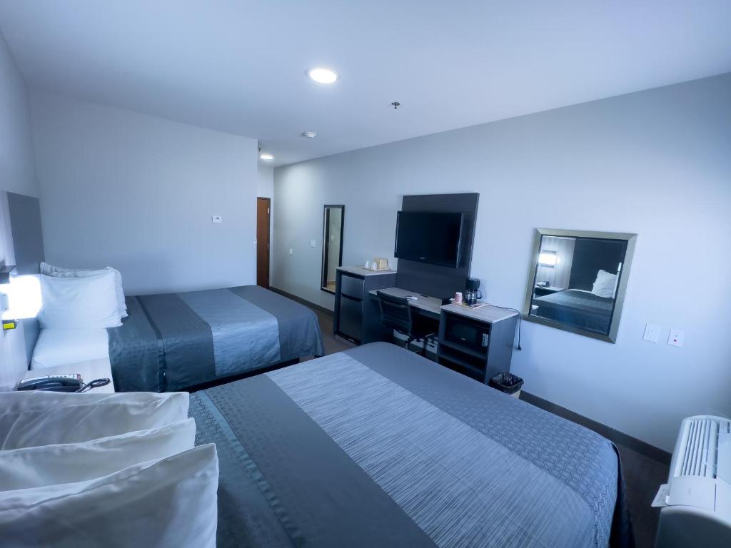 a hotel room with two beds and a television at American Inn Madill in Madill