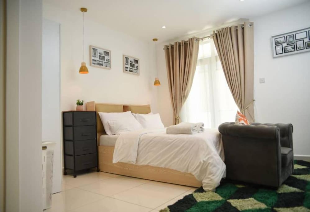 een slaapkamer met een bed, een stoel en een raam bij Luxury Suite 42m2 @ Embassy Gardens Cantonments in Cantonments