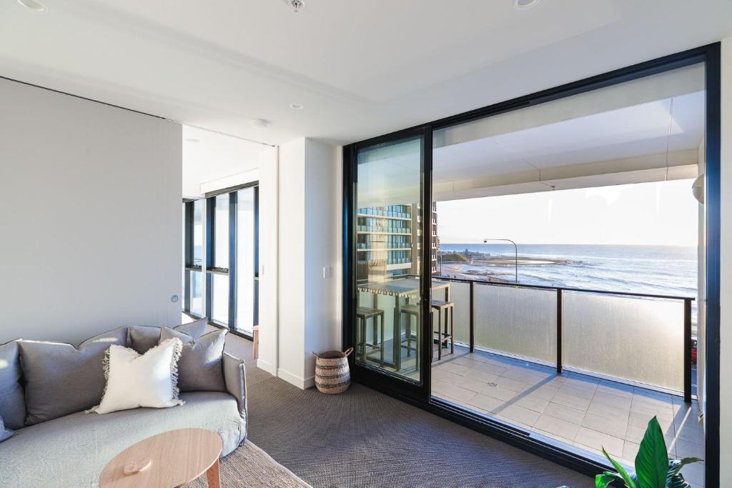 a living room with a couch and a view of the ocean at The Calm in Newcastle