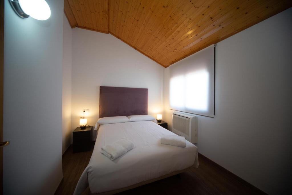 a bedroom with a white bed and a window at Apartamento Santa Bárbara in Castilleja de la Cuesta